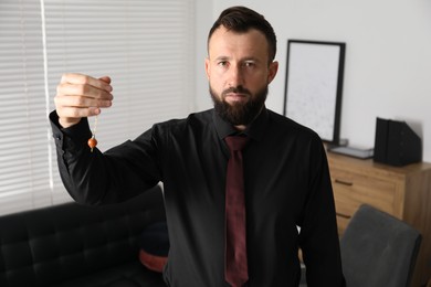 Photo of Hypnosis session. Man with pendulum in office