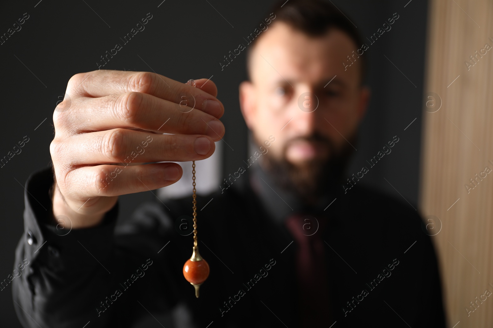 Photo of Hypnosis session. Man with pendulum in office, selective focus