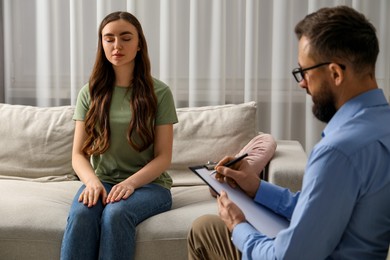 Photo of Psychologist working with patient during hypnosis session indoors