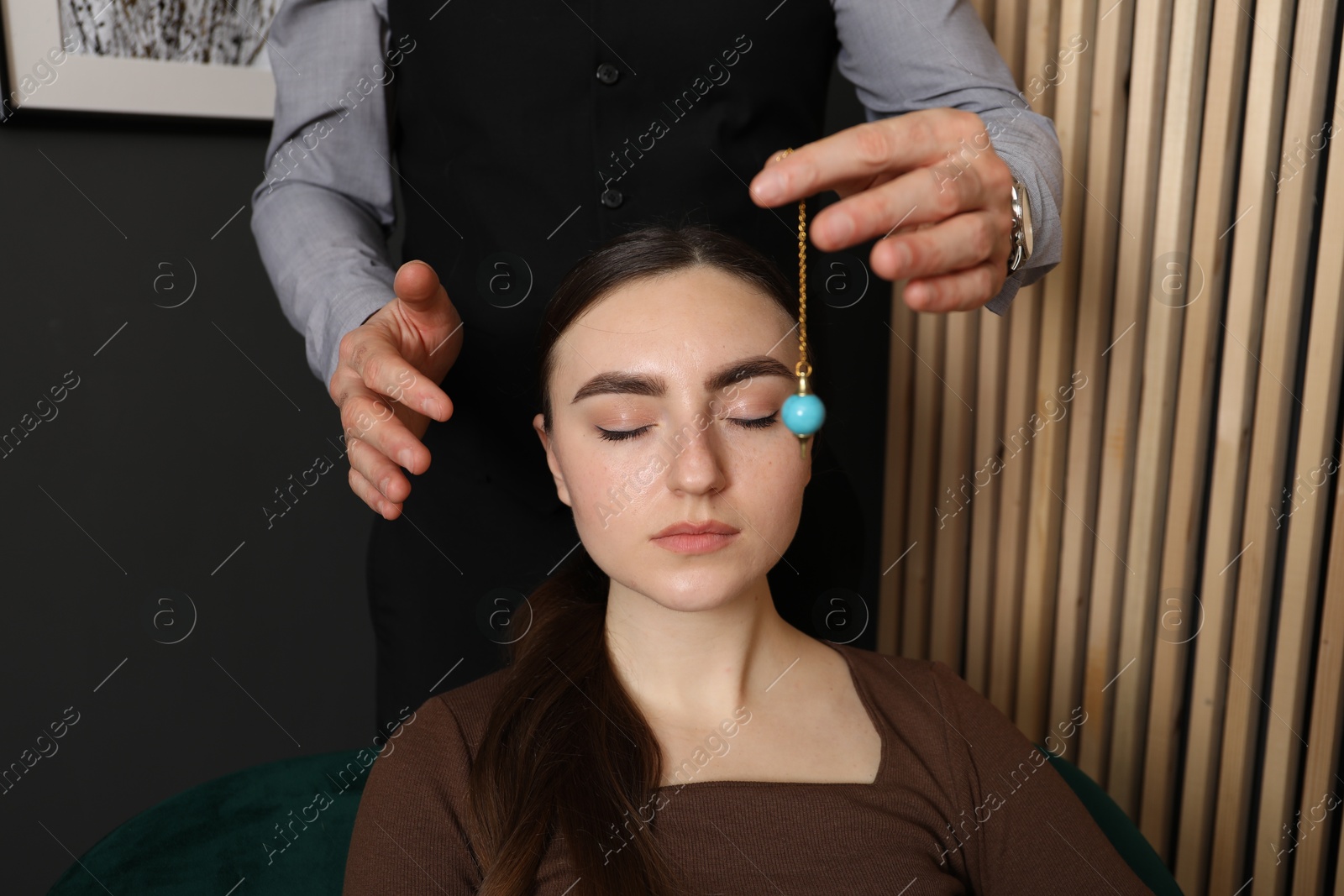 Photo of Psychologist using pendulum while working with patient during hypnosis session indoors, closeup