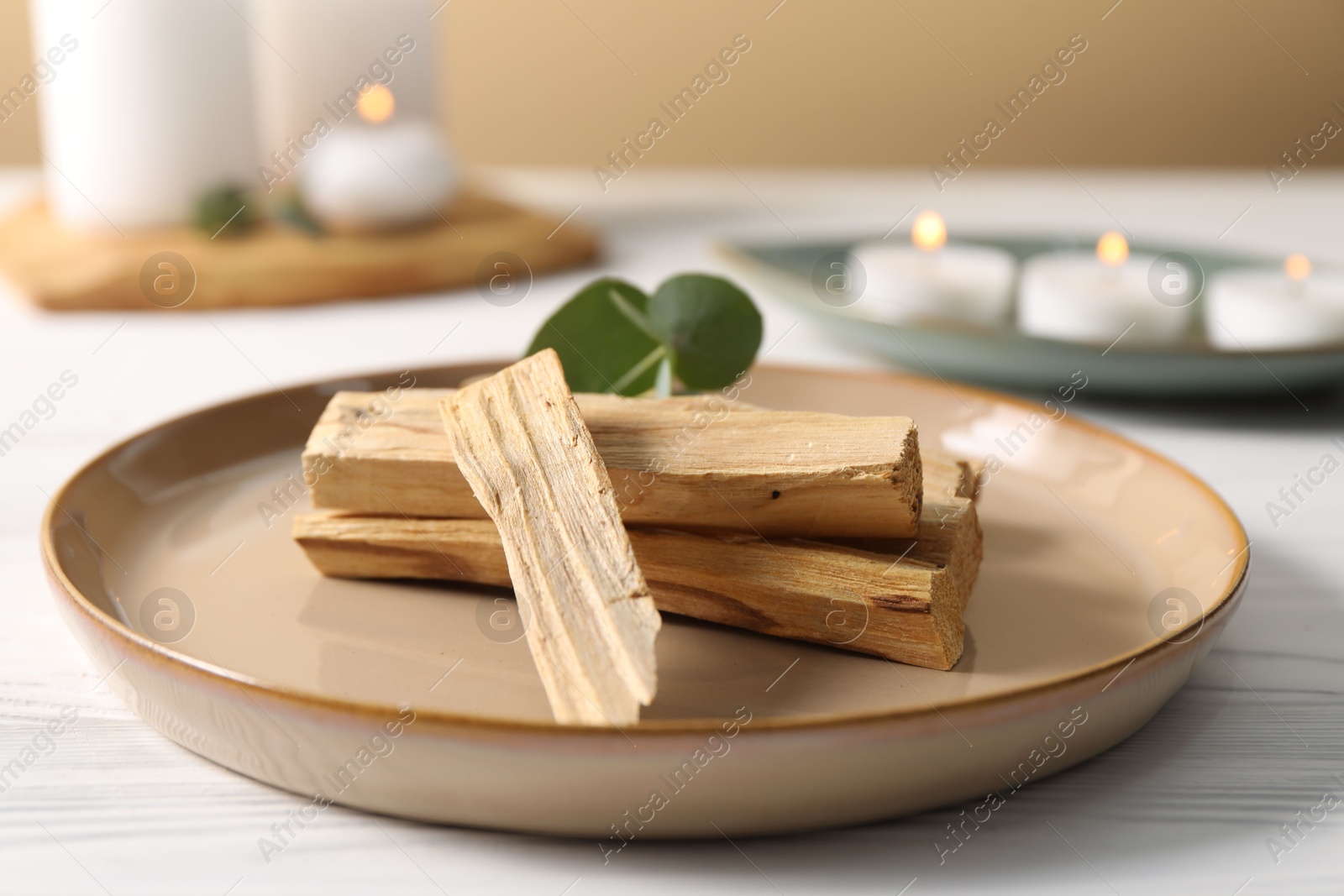 Photo of Palo santo sticks and eucalyptus leaves on white wooden table, closeup