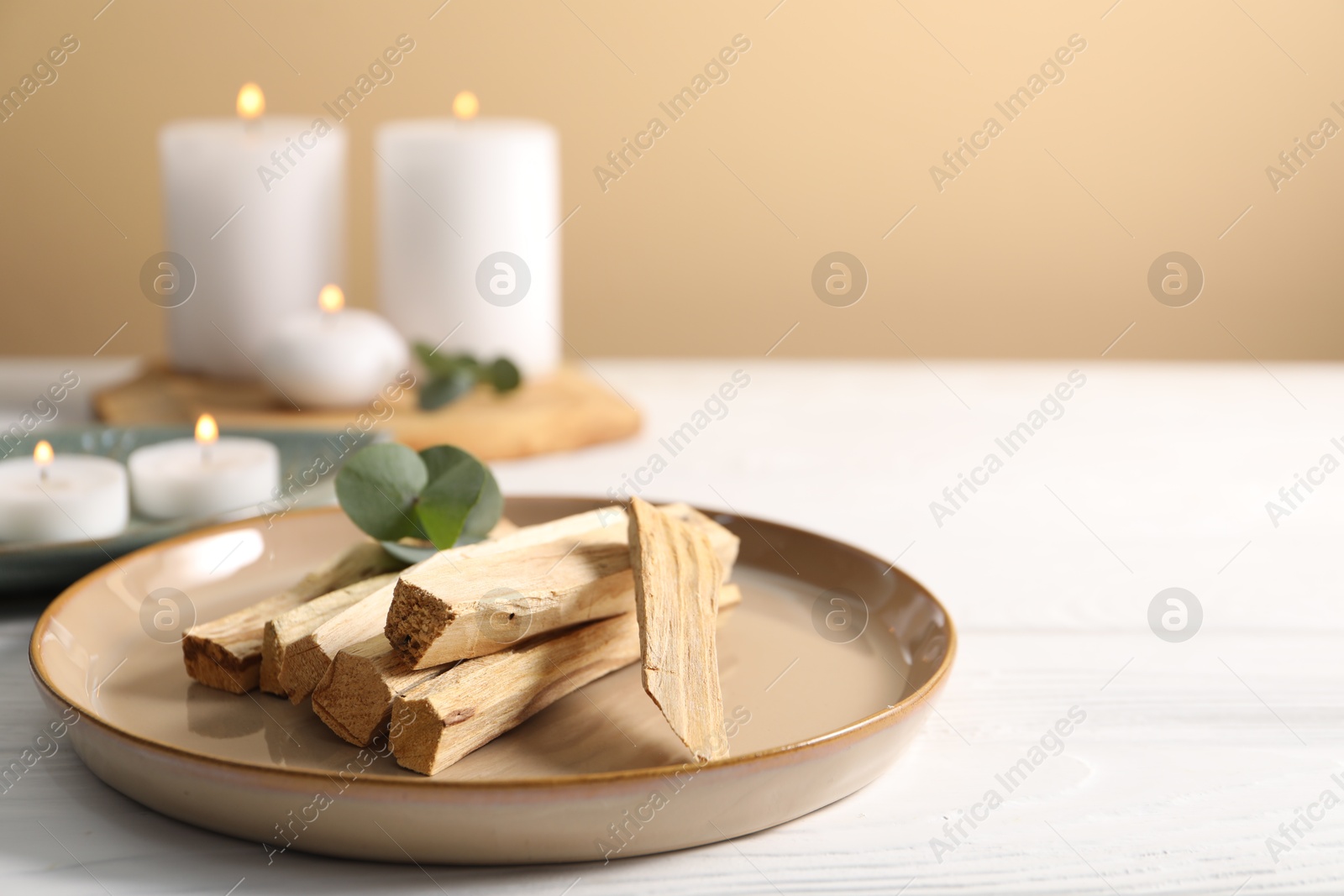 Photo of Palo santo sticks and eucalyptus leaves on white wooden table, closeup. Space for text