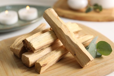 Photo of Palo santo sticks and eucalyptus leaves on table, closeup