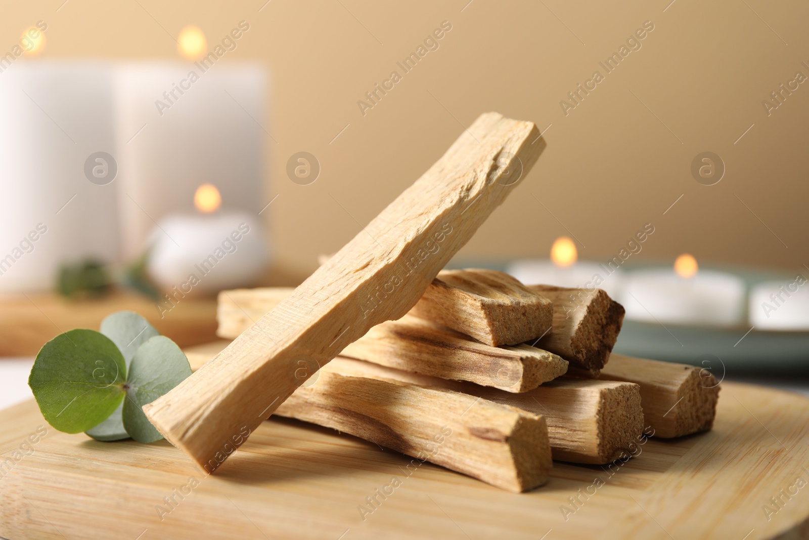 Photo of Palo santo sticks and eucalyptus leaves on wooden board, closeup