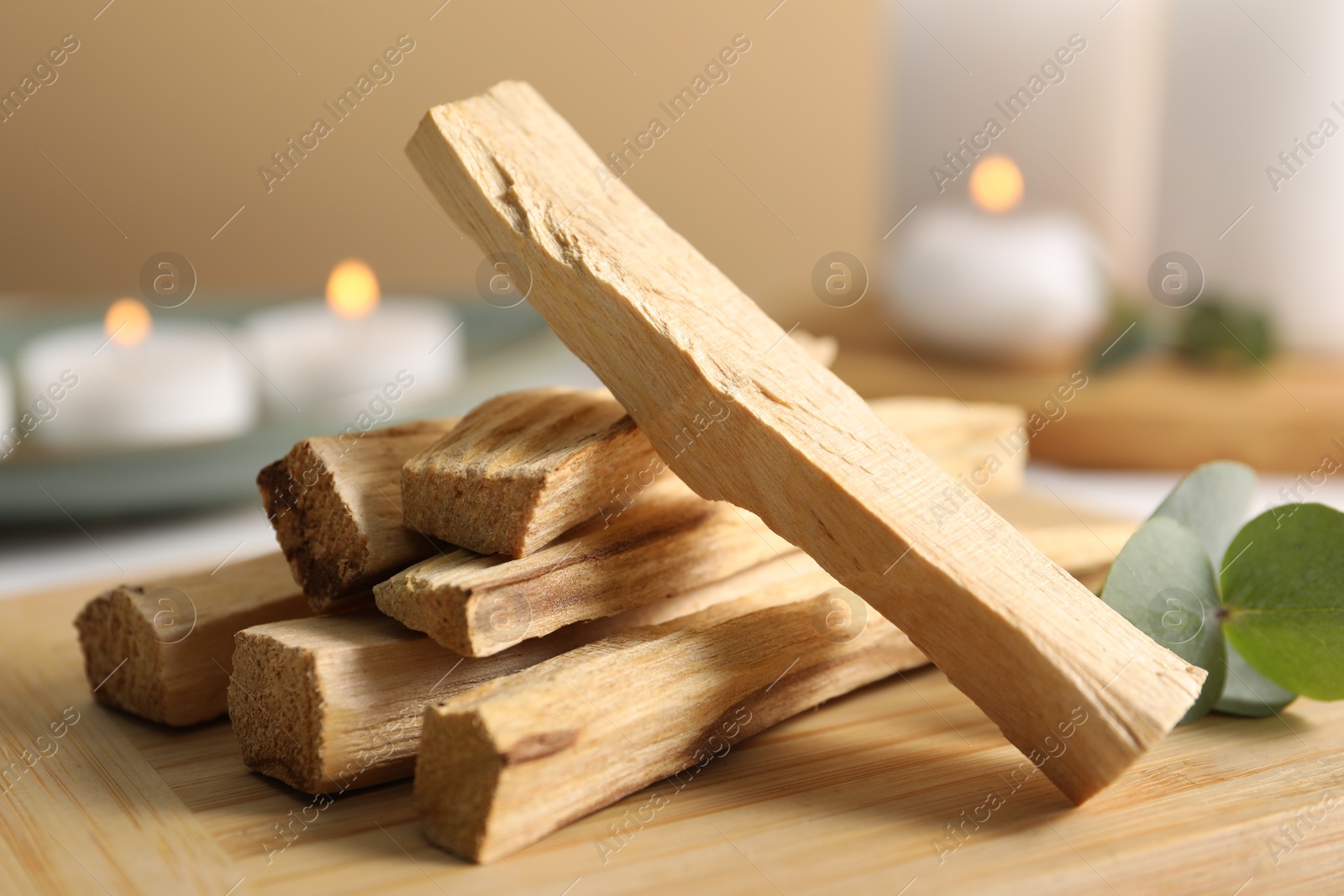 Photo of Palo santo sticks and eucalyptus leaves on wooden board, closeup