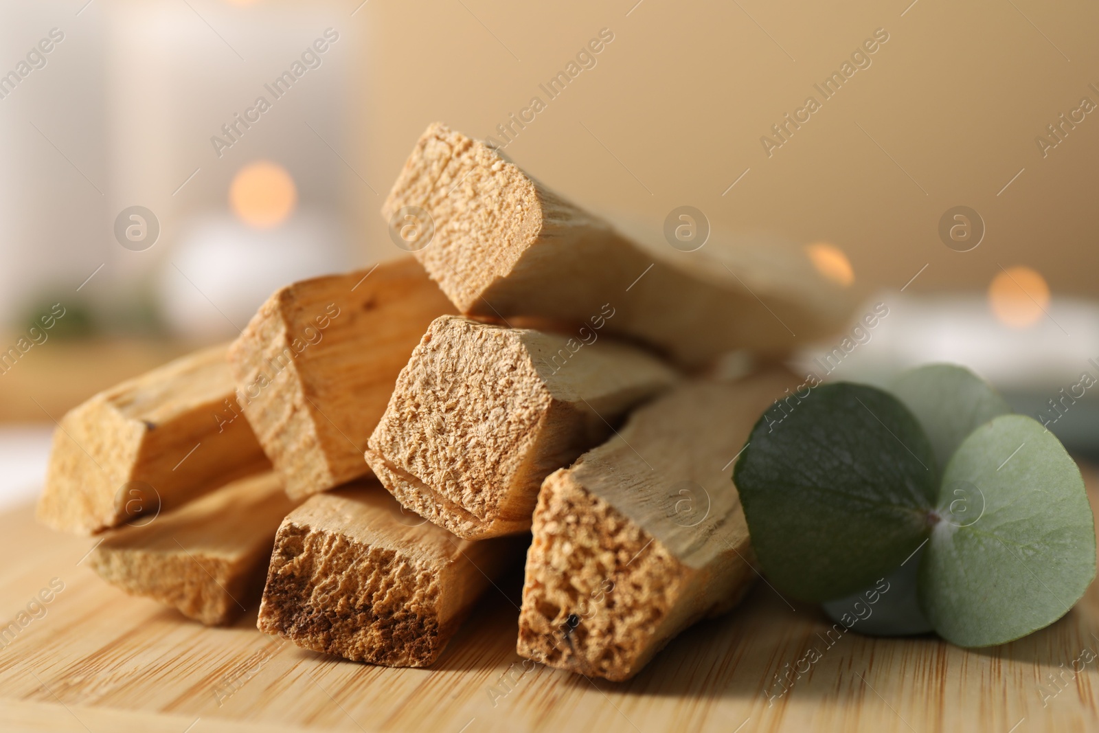 Photo of Palo santo sticks and eucalyptus leaves on wooden board, closeup