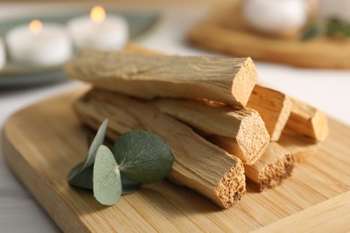 Photo of Palo santo sticks and eucalyptus leaves on table, closeup