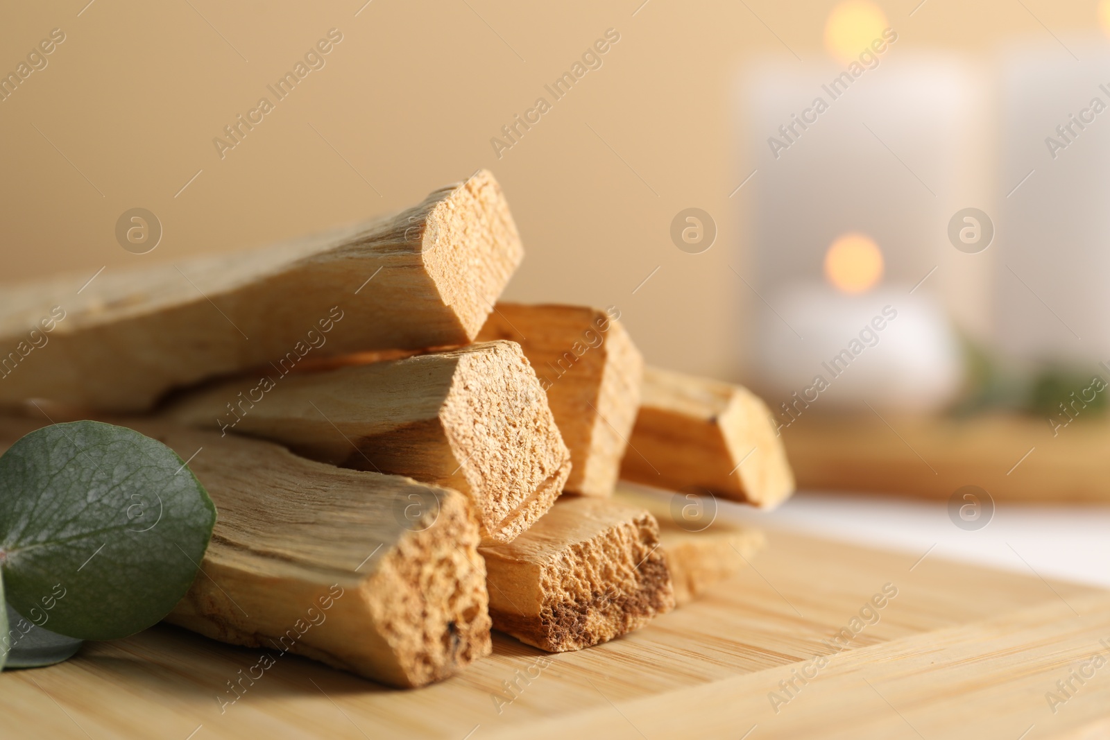 Photo of Palo santo sticks and eucalyptus leaves on wooden board, closeup