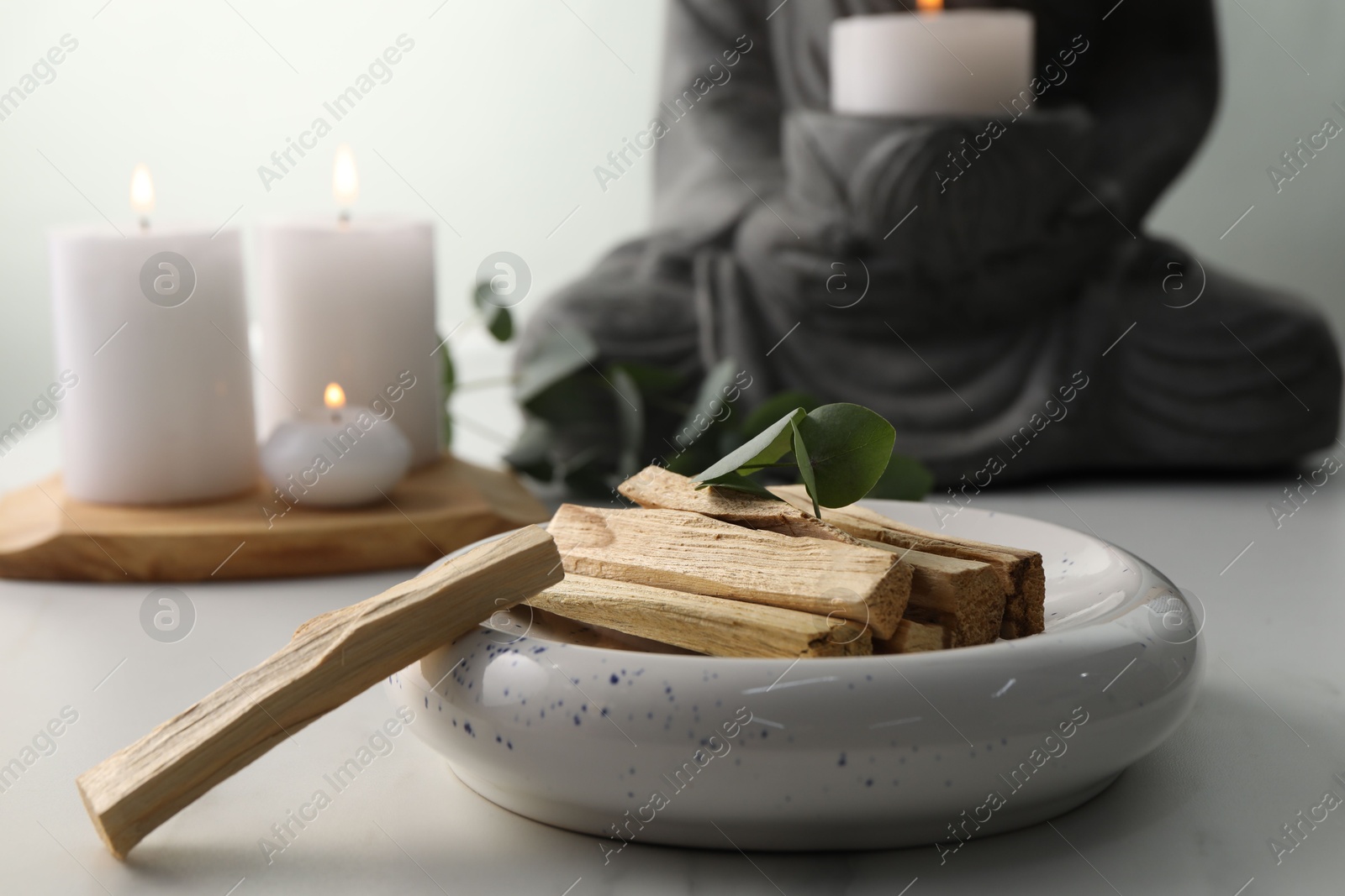 Photo of Palo santo sticks and eucalyptus leaves on white table, closeup