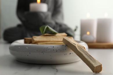 Photo of Palo santo sticks on white marble table, closeup