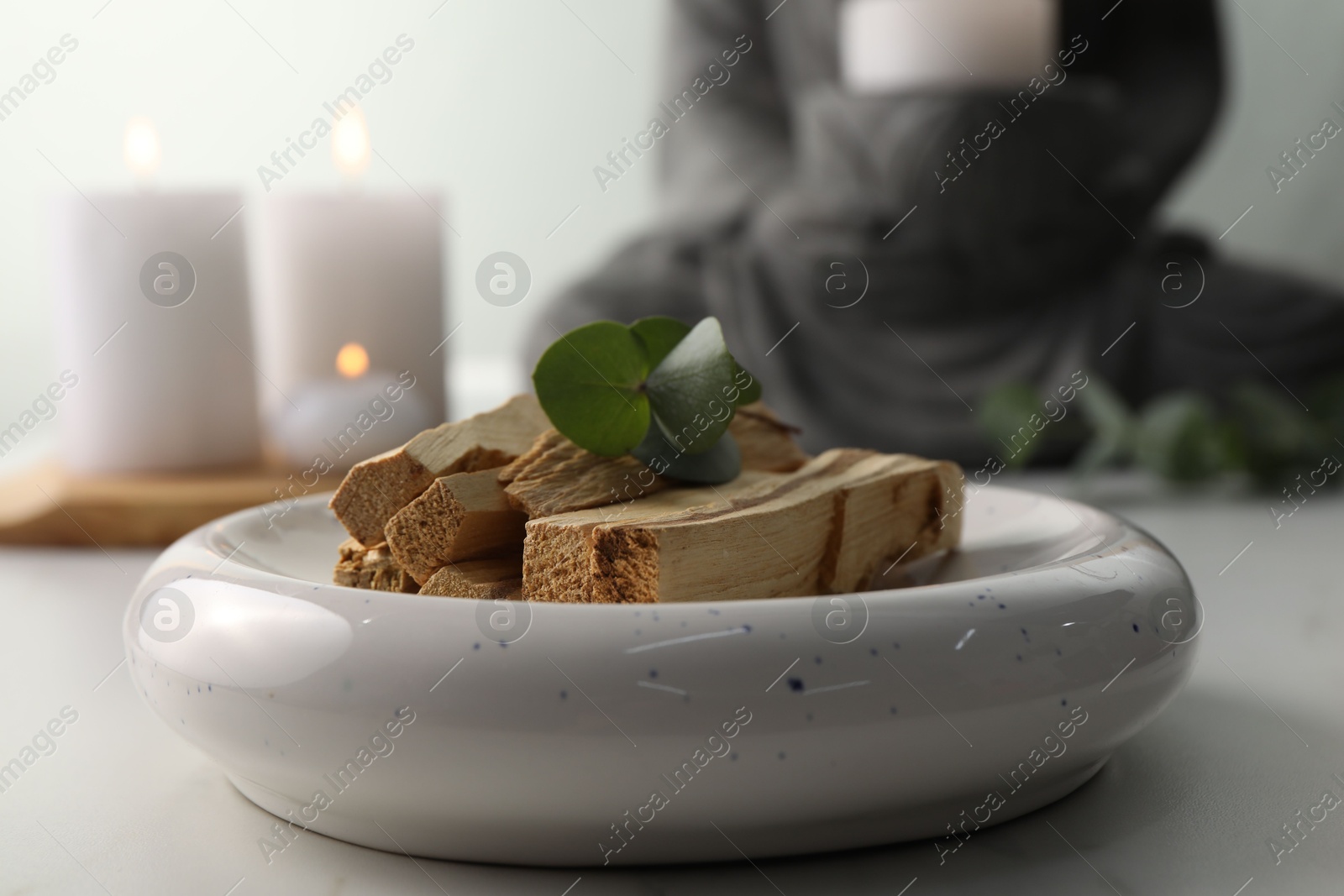 Photo of Palo santo sticks and eucalyptus leaves on white table, closeup