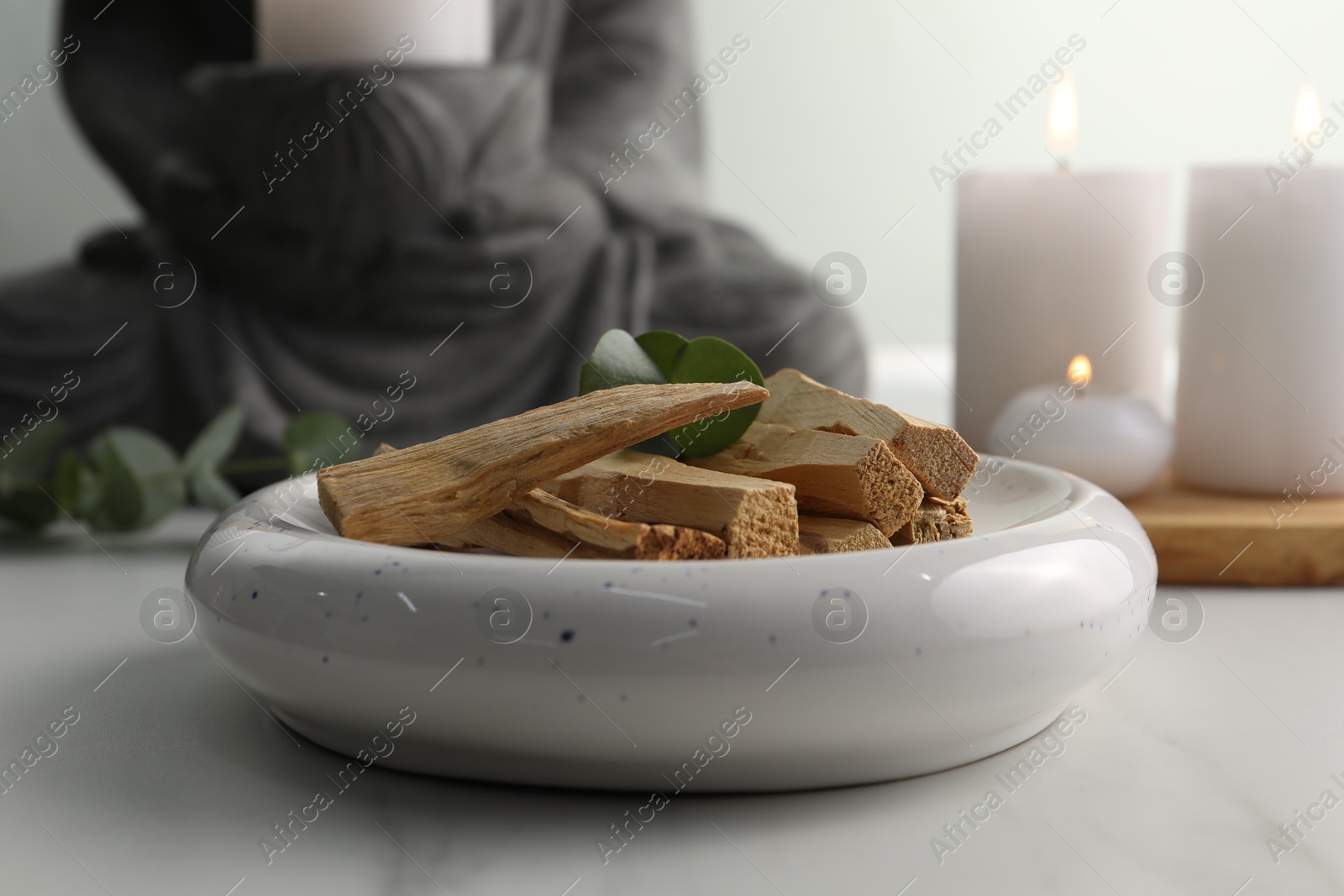 Photo of Palo santo sticks and eucalyptus leaves on white table, closeup