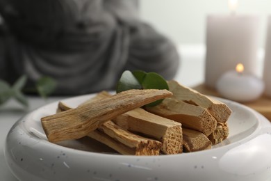 Photo of Palo santo sticks and eucalyptus leaves on table, closeup