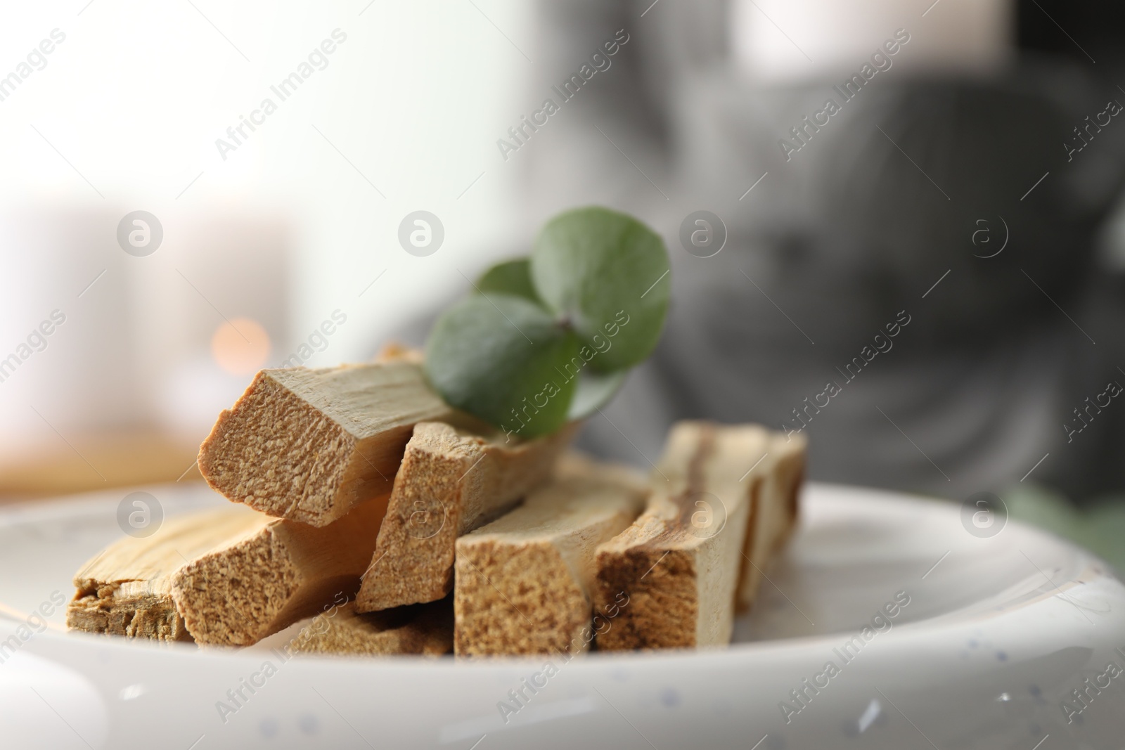 Photo of Palo santo sticks and eucalyptus leaves on blurred background, closeup