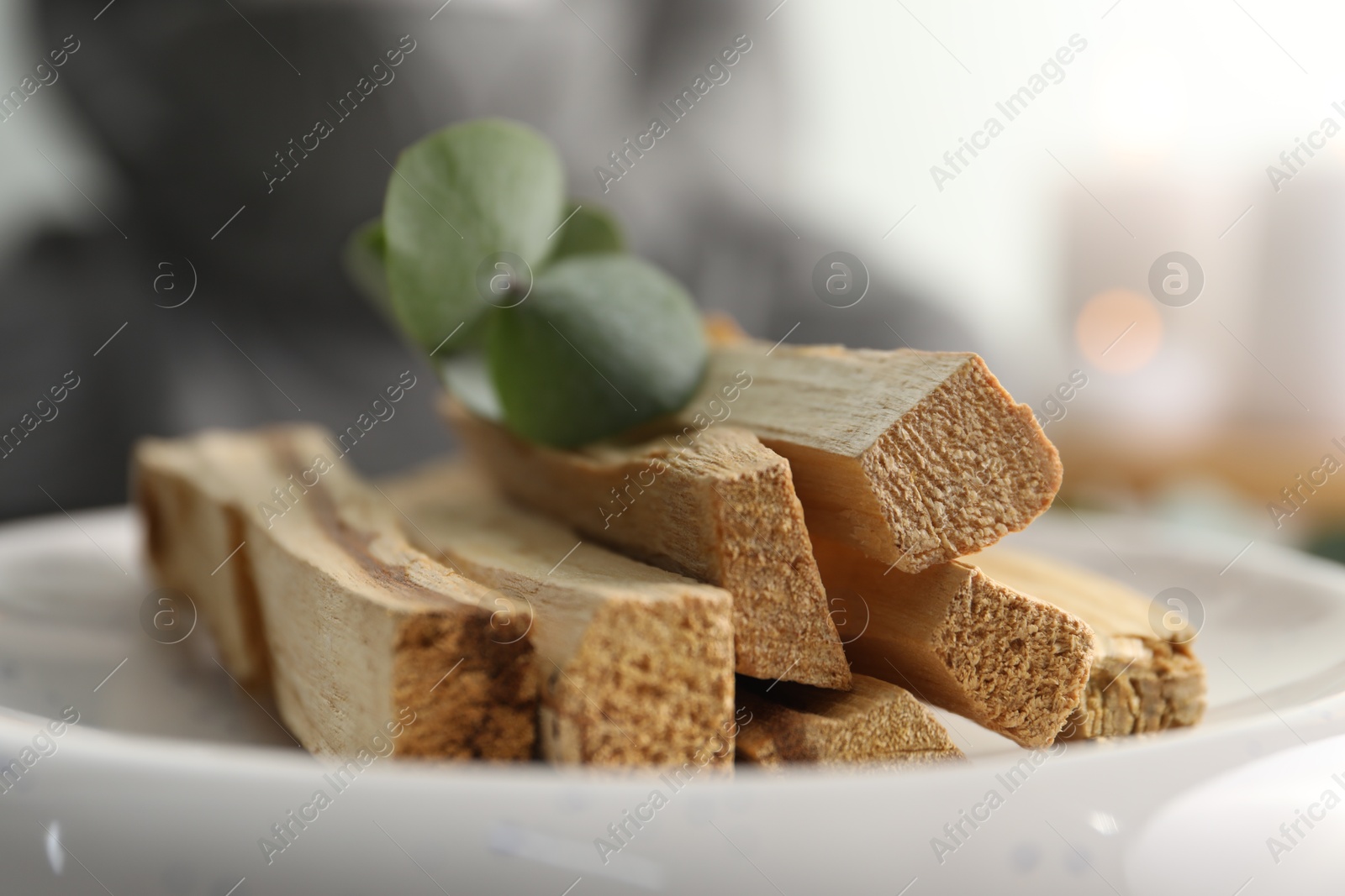 Photo of Palo santo sticks and eucalyptus leaves on blurred background, closeup