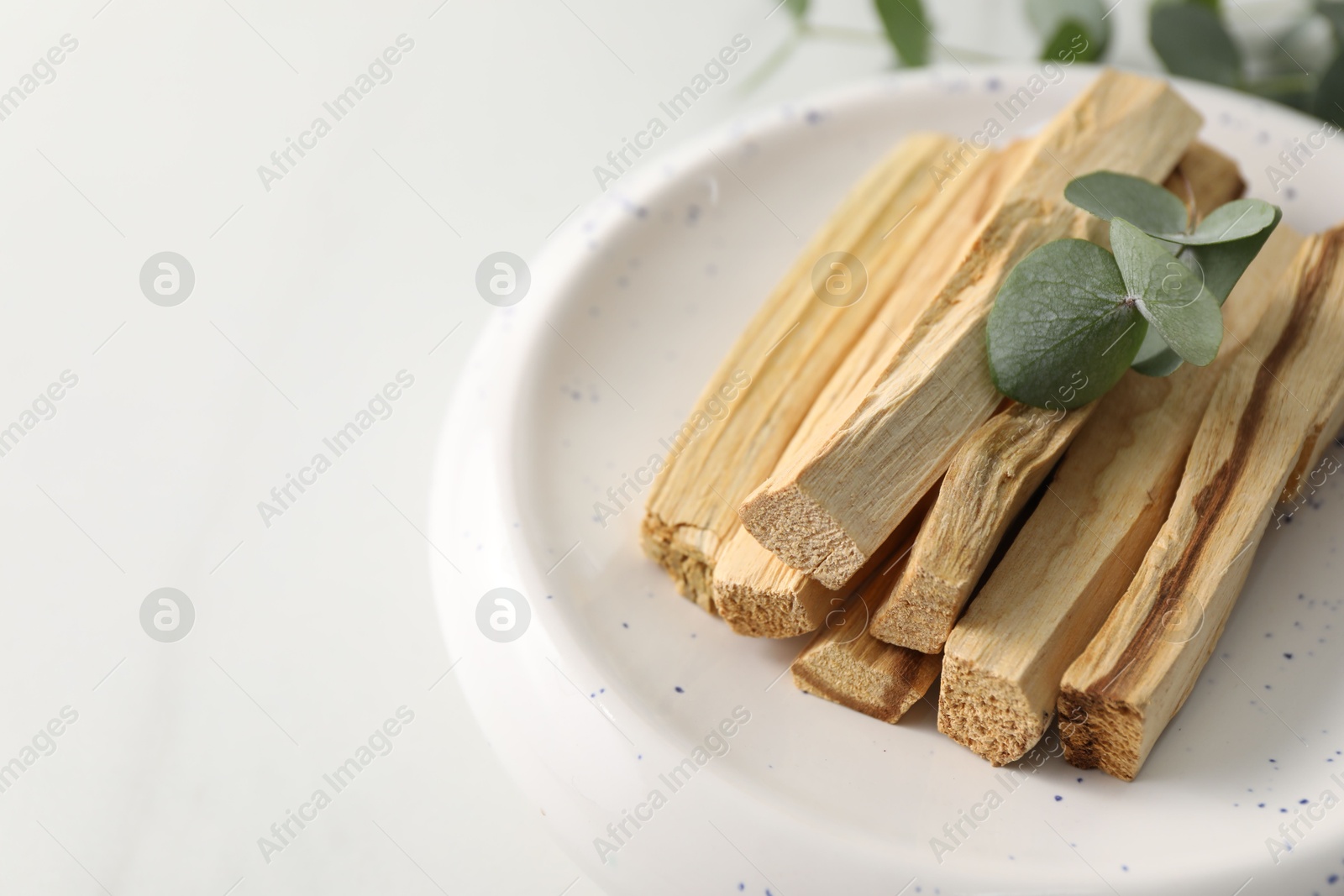 Photo of Palo santo sticks and eucalyptus leaves on white table, closeup. Space for text