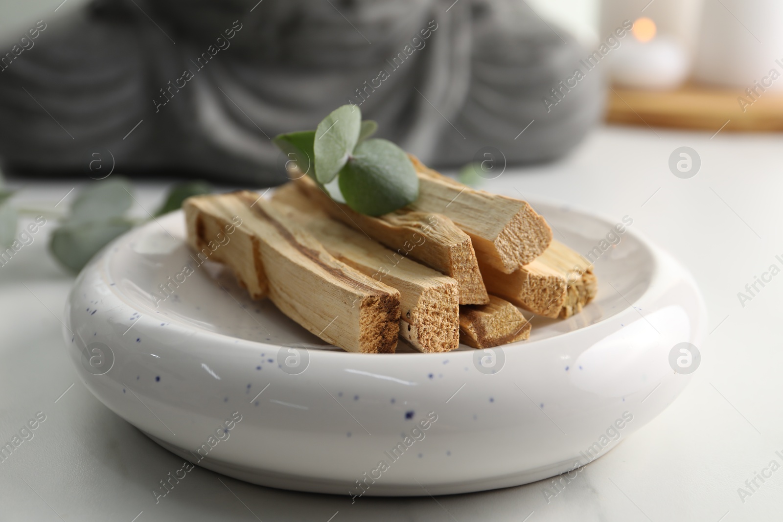 Photo of Palo santo sticks and eucalyptus leaves on white table, closeup