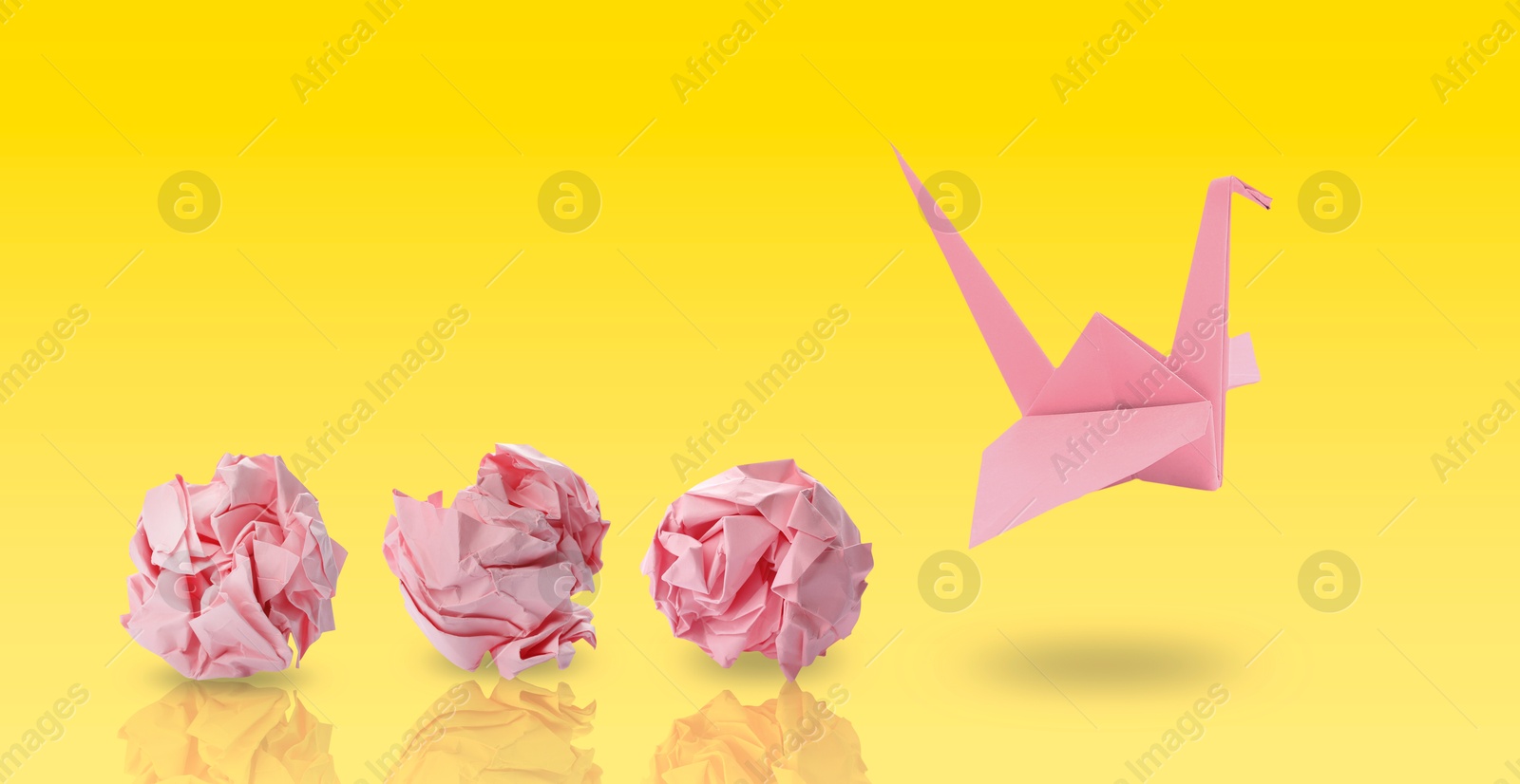 Image of Pink origami crane and crumpled paper balls on yellow gradient background, banner design. Transformation or new ideas concept