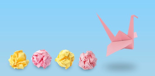 Image of Pink origami crane and crumpled paper balls on light blue background, banner design. Transformation or new ideas concept