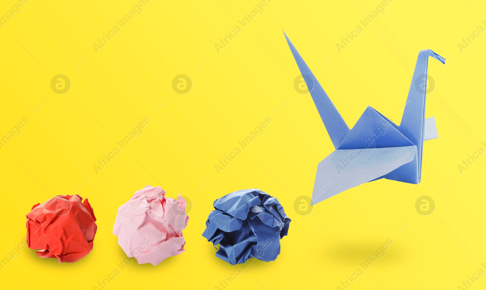 Image of Blue origami crane and crumpled paper balls on yellow background, banner design. Transformation or new ideas concept