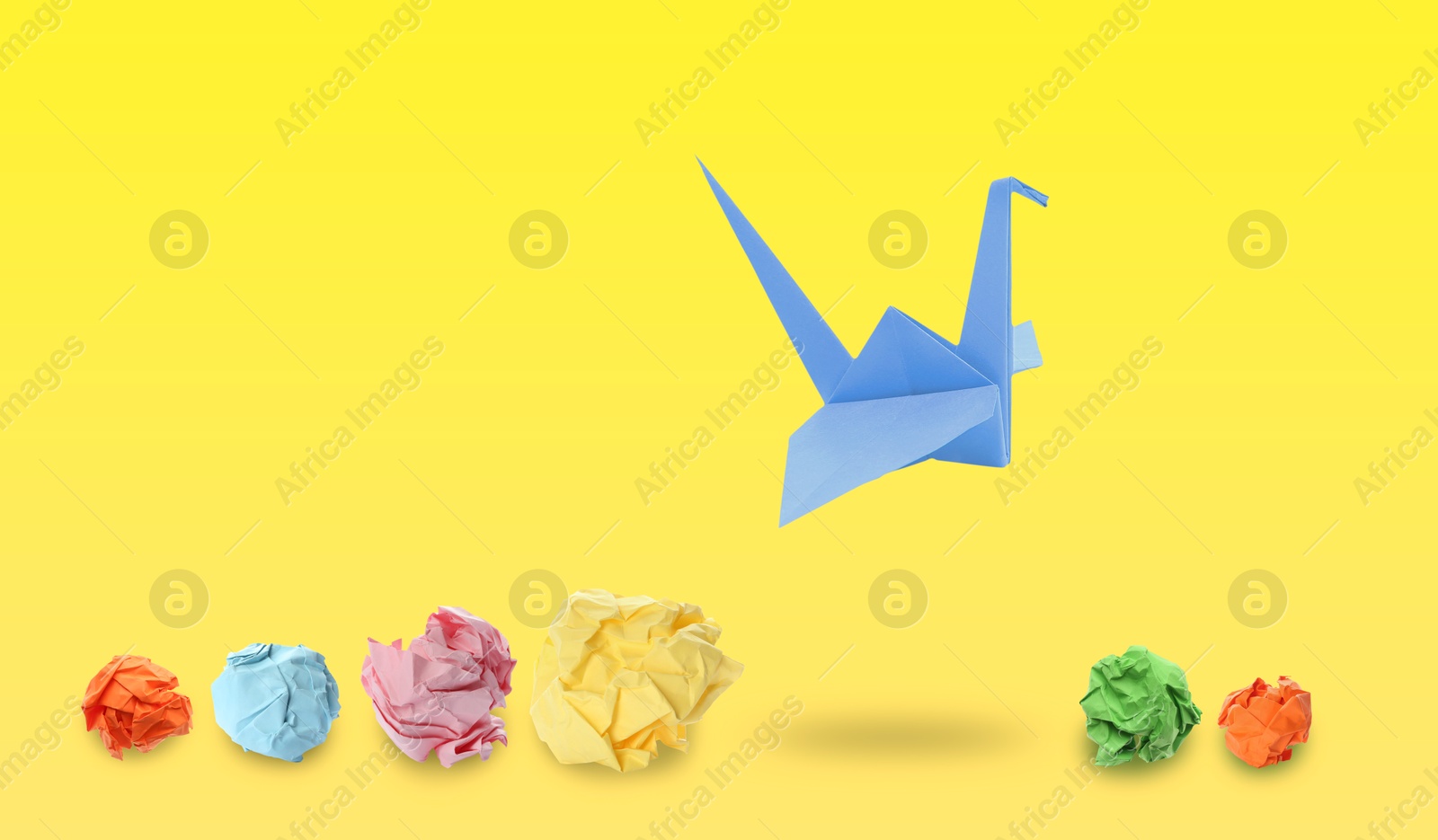 Image of Blue origami crane and crumpled paper balls on yellow gradient background, banner design. Transformation or leadership concept