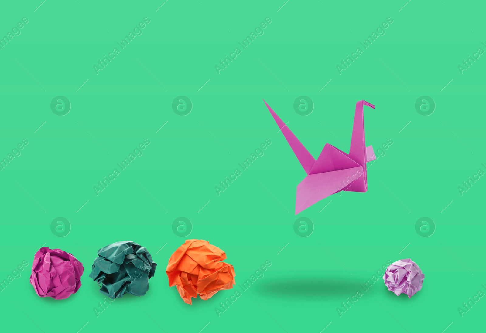 Image of Magenta origami crane and crumpled paper balls on aquamarine color background. Transformation or leadership concept