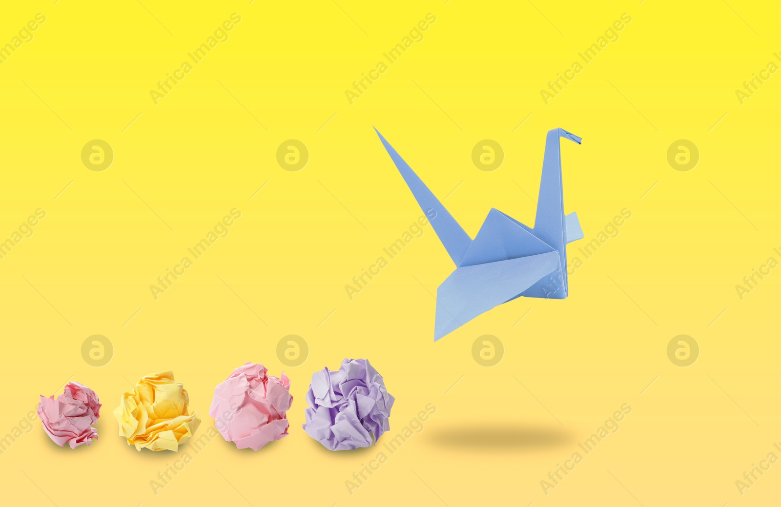 Image of Blue origami crane and crumpled paper balls on yellow gradient background. Transformation or new ideas concept