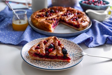 Photo of Piece of delicious currant pie with fresh berries served on white table