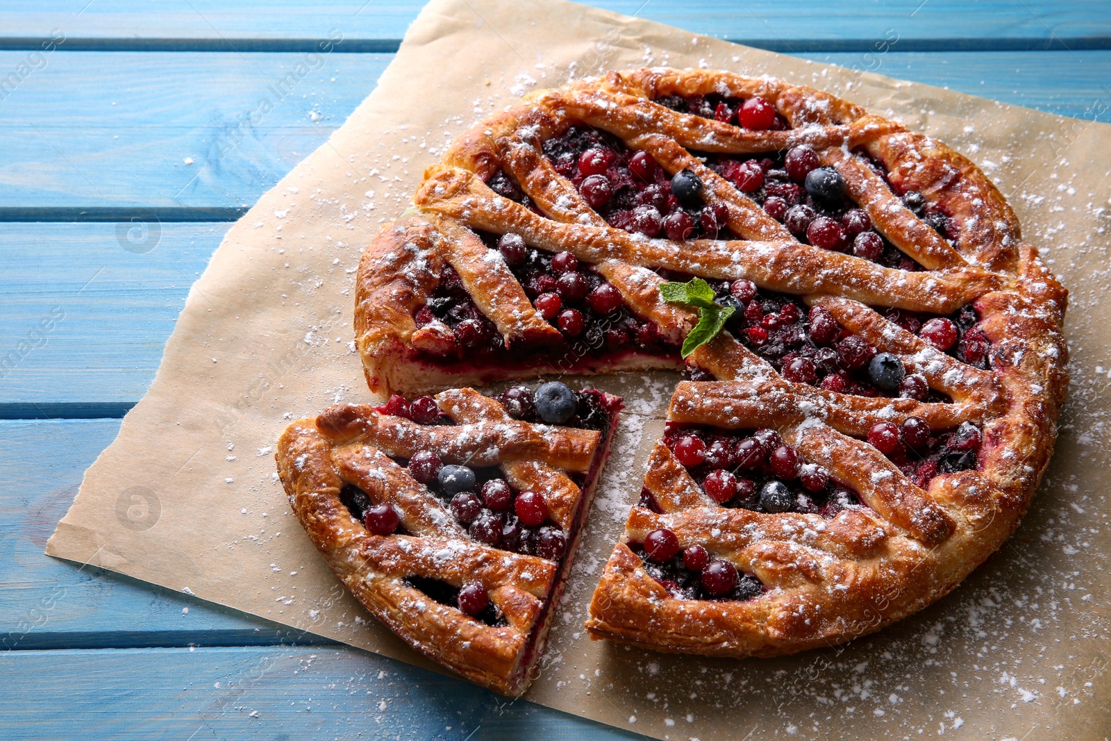 Photo of Delicious cut currant pie and fresh berries on blue wooden table