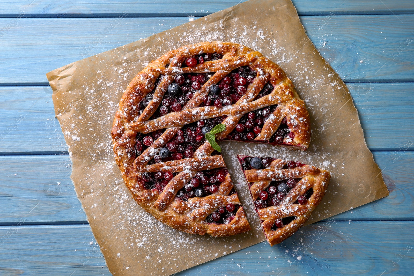 Photo of Delicious cut currant pie and fresh berries on blue wooden table, flat lay