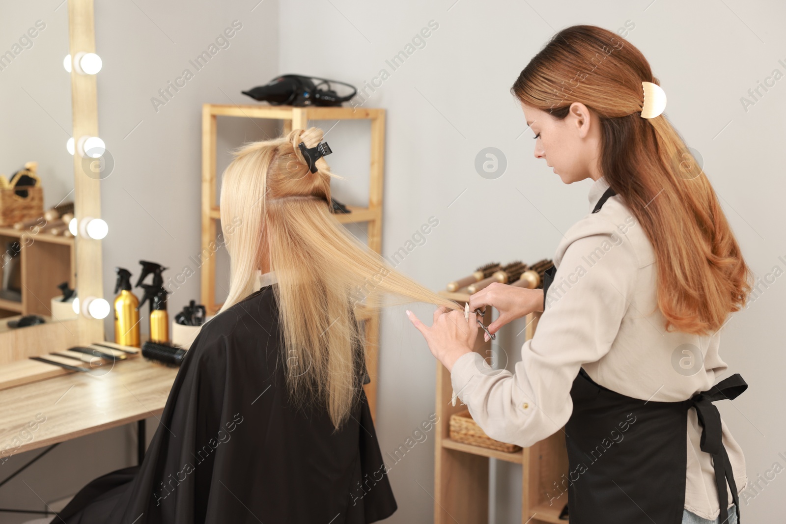 Photo of Hairdresser cutting client's hair with scissors in salon