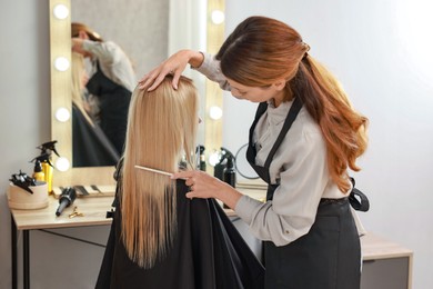 Photo of Professional hairdresser combing woman's hair in salon