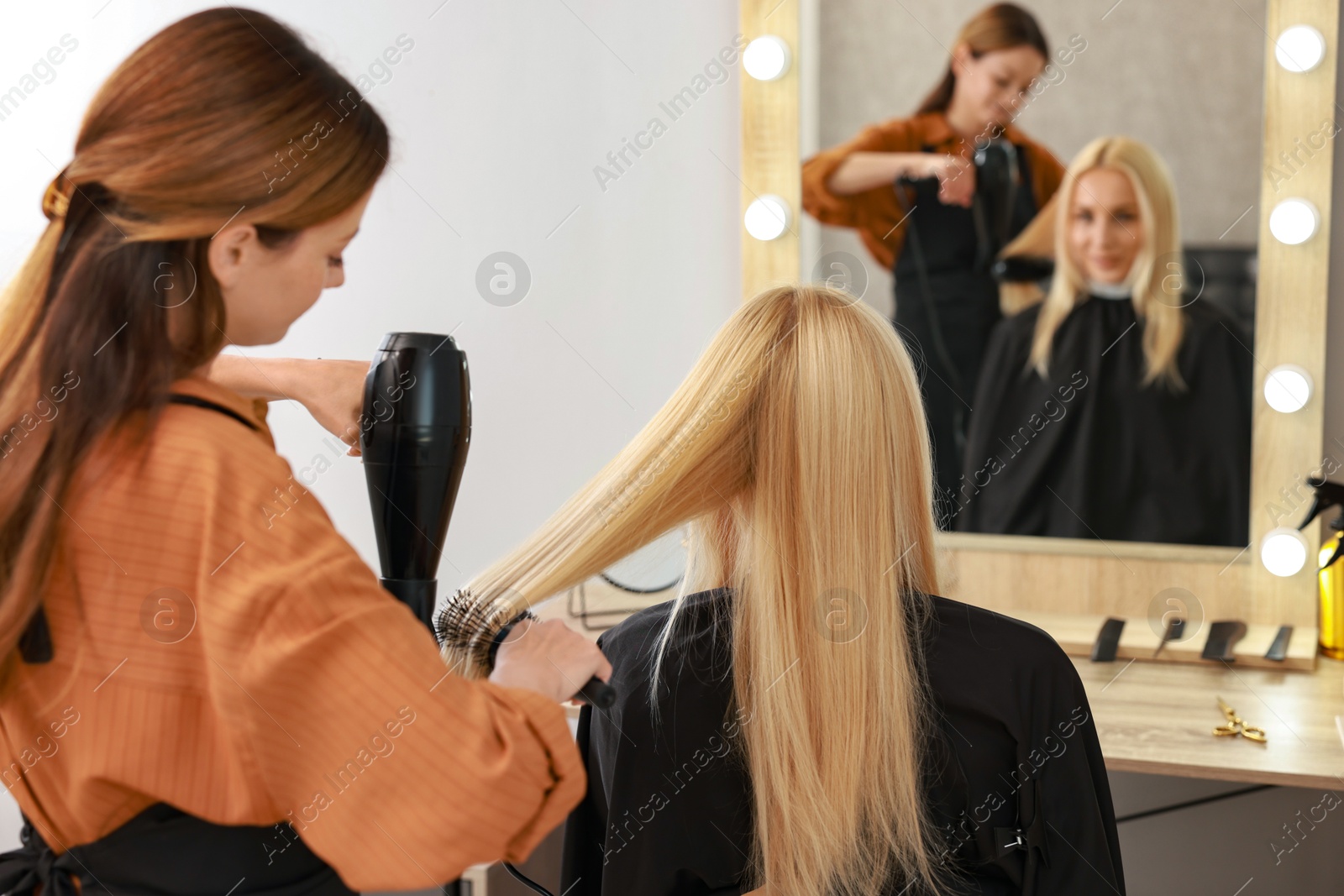 Photo of Hairdresser blow drying client's hair in salon