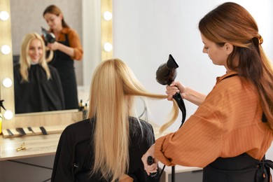 Photo of Hairdresser blow drying client's hair in salon