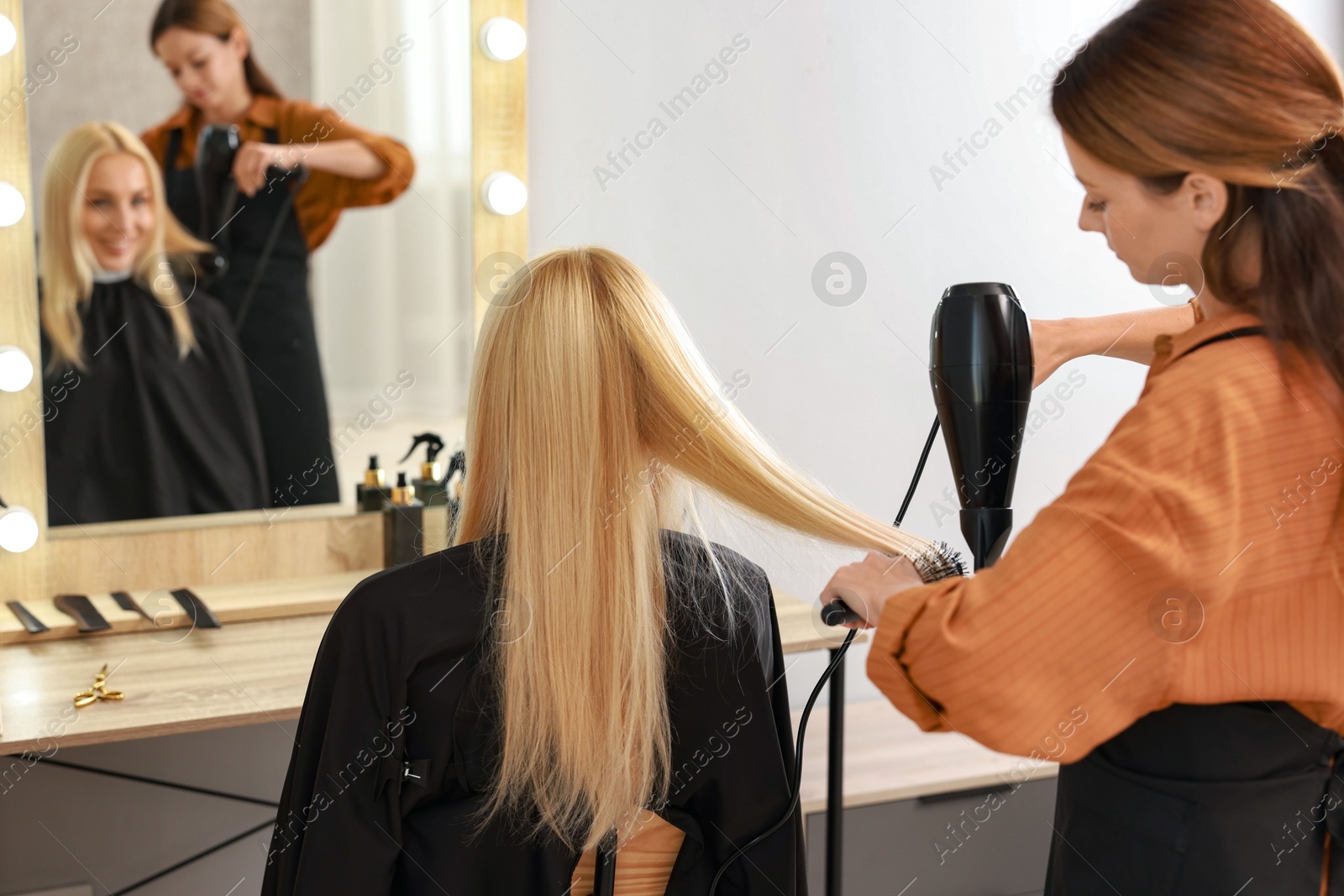 Photo of Hairdresser blow drying client's hair in salon