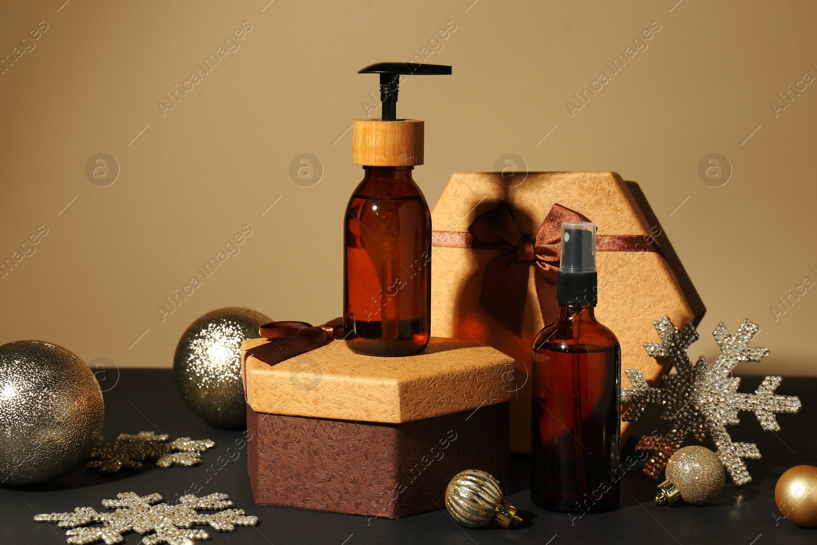 Photo of Cosmetic products as Christmas present, gift boxes and festive decor on table against dark beige background