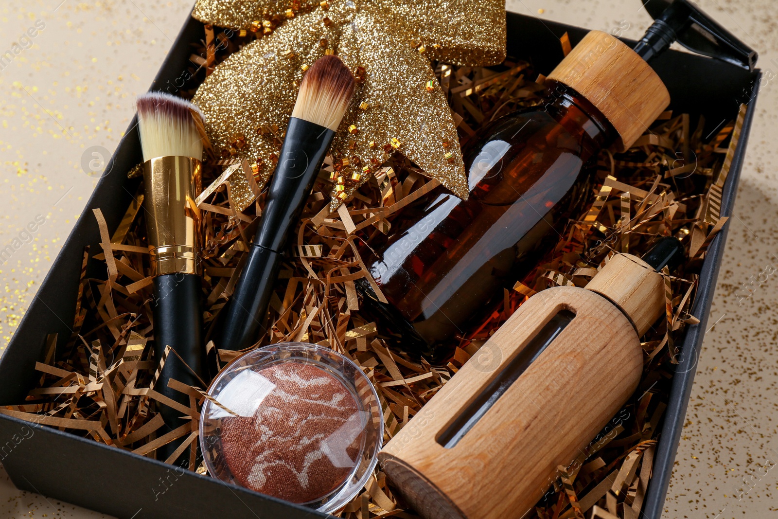 Photo of Cosmetic products in box as Christmas gift on beige background, closeup