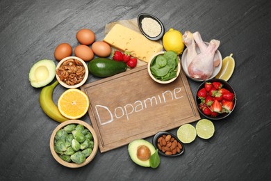 Photo of Wooden board with word Dopamine and different fresh products on grey textured table, flat lay