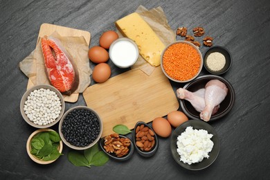 Photo of Different fresh products rich in estrogen and wooden board on grey textured table, flat lay