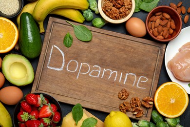 Photo of Wooden board with word Dopamine and different fresh products on grey table, flat lay