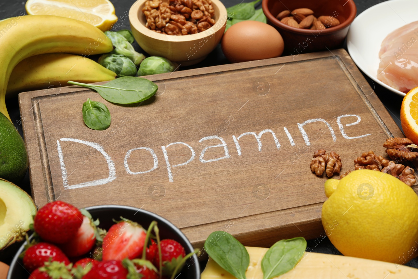 Photo of Wooden board with word Dopamine and different fresh products on grey table