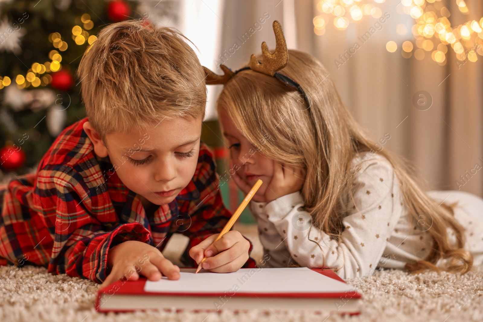 Photo of Little kids writing letter to Santa Claus on floor at home. Christmas celebration