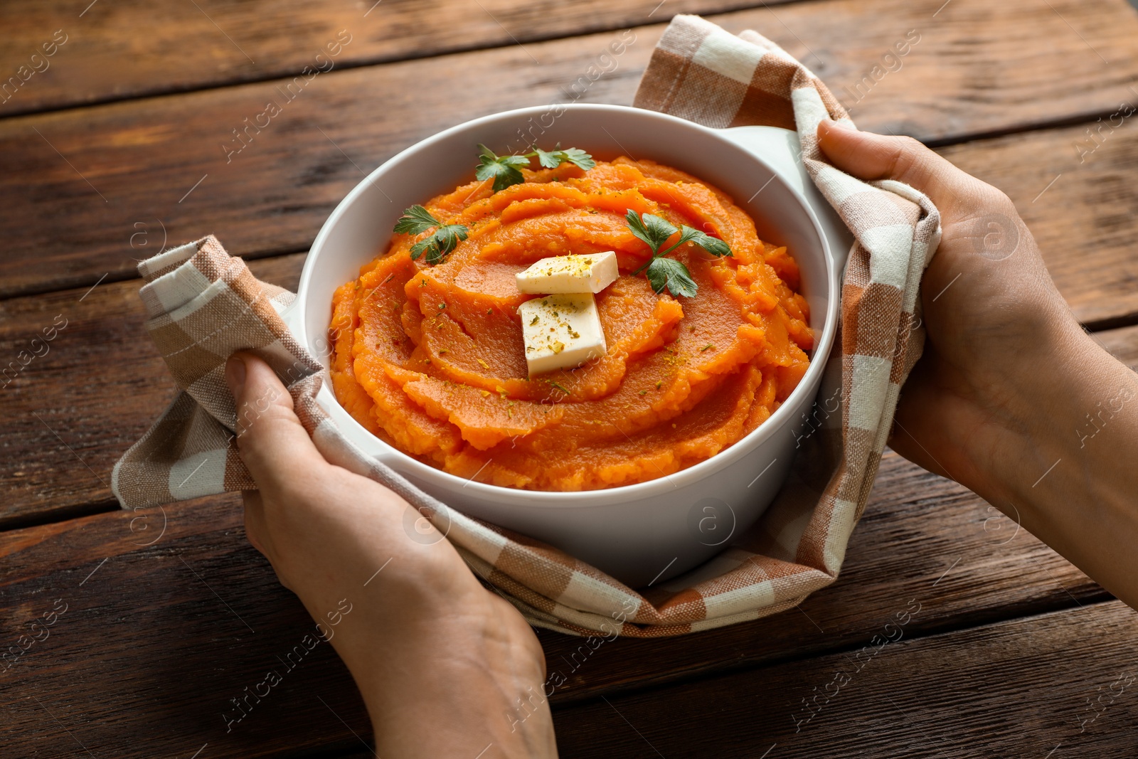 Woman with bowl of tasty mashed sweet potato at wooden table, closeup Photo of Woman with bowl of tasty mashed sweet potato at wooden table, closeup
