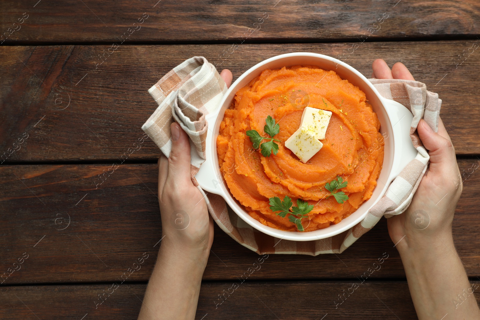 Woman with bowl of tasty mashed sweet potato at wooden table, top view Photo of Woman with bowl of tasty mashed sweet potato at wooden table, top view