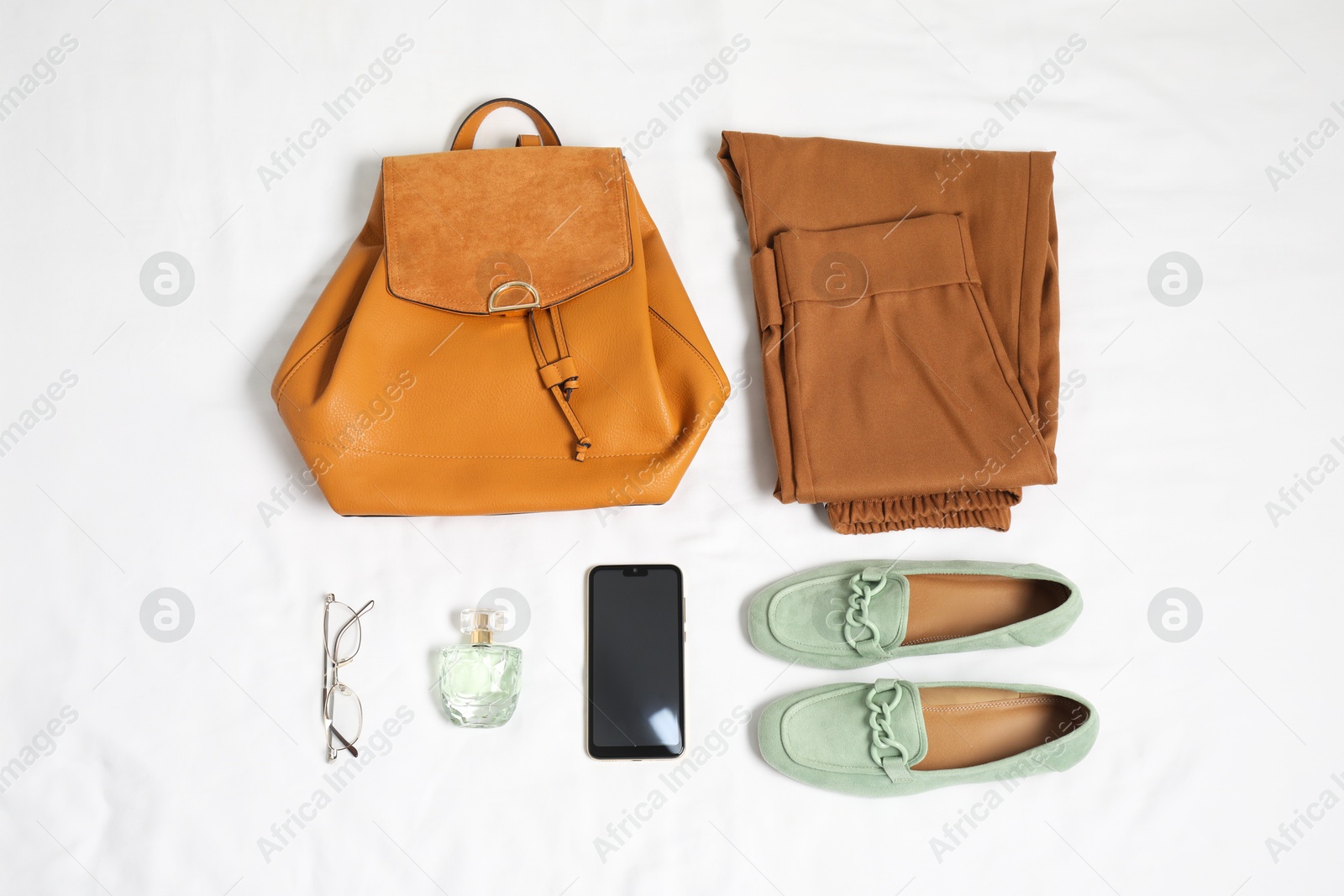 Photo of Stylish outfit with backpack on white fabric, flat lay