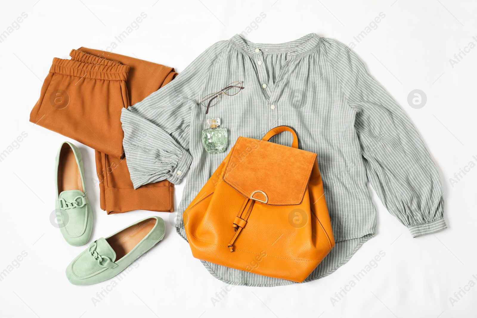 Photo of Stylish outfit with backpack on white fabric, flat lay