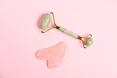 Photo of Face roller and gua sha tool on pink background, top view