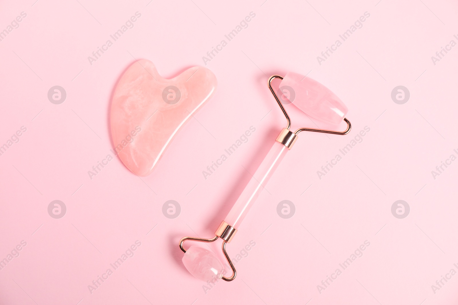 Photo of Face roller and gua sha tool on pink background, top view