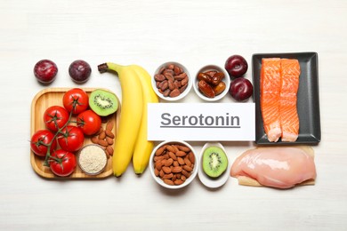 Photo of Word Serotonin and products on white wooden table, flat lay