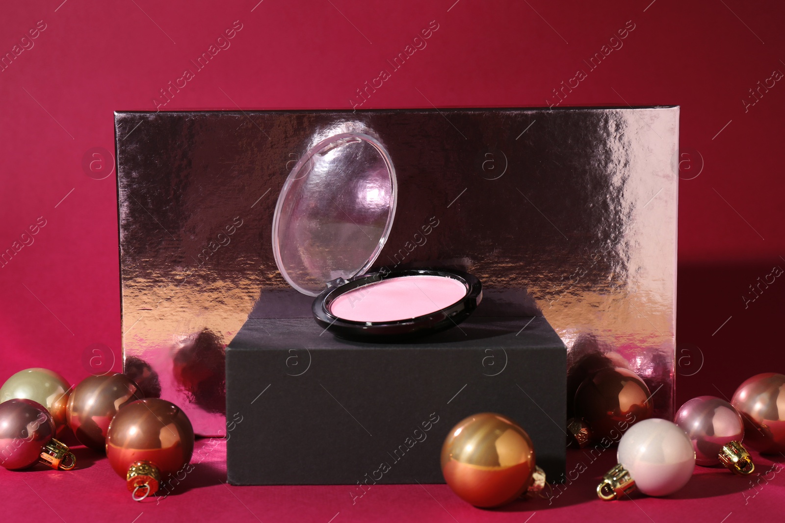 Photo of Christmas gift. Luxury cosmetic product and festive balls on dark pink background